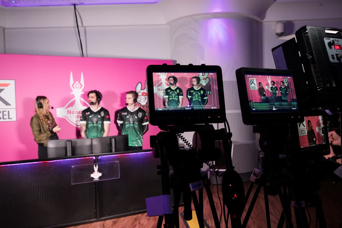 The Neosurf Cup 2020 arena — an esports stage under pink and purple light, a seated crowd and a League of Legends match on the big screen