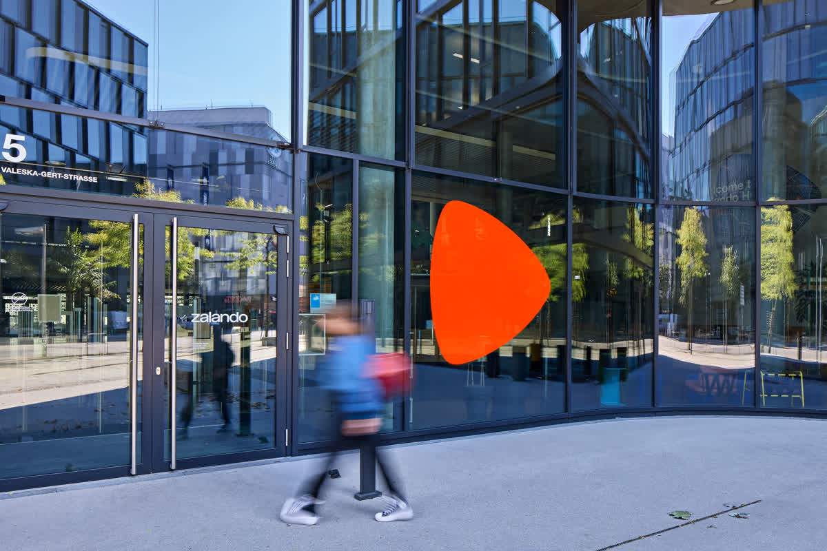 Siedziba Zalando w Berlinie z oficjalnych materiałów prasowych marki — pomarańczowy znak Zalando na szklanej fasadzie